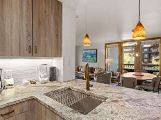 This modern kitchen boasts sleek, wood-grain cabinetry and a stunning granite countertop with an integrated sink and brass faucet.