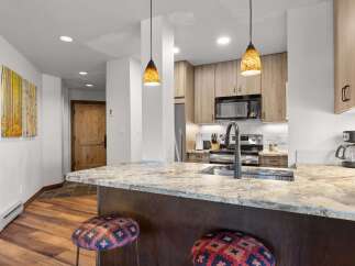 This modern kitchen boasts a spacious granite island with a deep sink and a sleek faucet, perfect for meal preparation and casual dining.