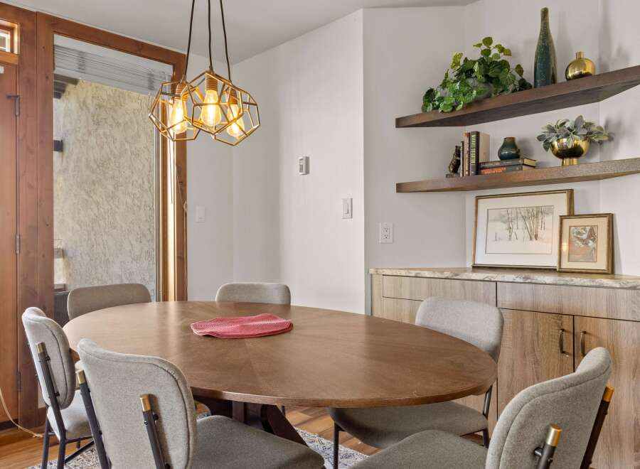 This dining area features a stylish oval wooden table surrounded by comfortable upholstered chairs, perfect for intimate gatherings.