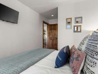 This bedroom offers a comfortable and stylish retreat, featuring a plush bed adorned with decorative pillows and a calming blue quilt.