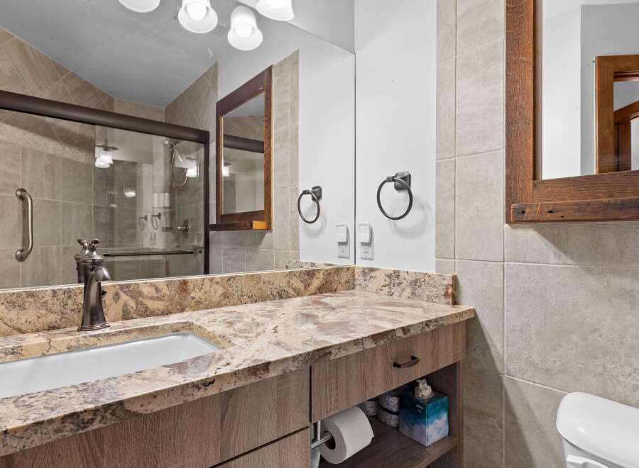 This bathroom features a granite countertop with an undermount sink and a bronze faucet.
