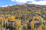 Experience the beauty of autumn in this stunning mountain community, featuring a cluster of residential buildings nestled amongst vibrant fall foliage.