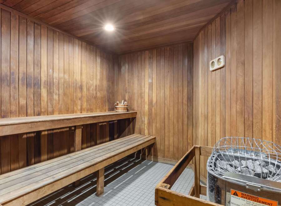 Experience ultimate relaxation in this luxurious wooden sauna, featuring comfortable tiered seating and a modern electric heater.