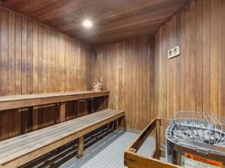 Experience ultimate relaxation in this luxurious wooden sauna, featuring comfortable tiered seating and a modern electric heater.
