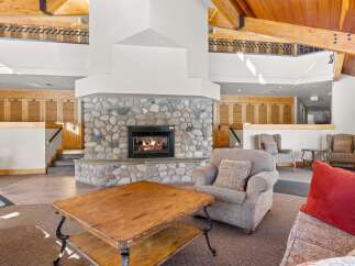 Experience rustic charm in this spacious living area, featuring a magnificent floor-to-ceiling stone fireplace that serves as the heart of the home.