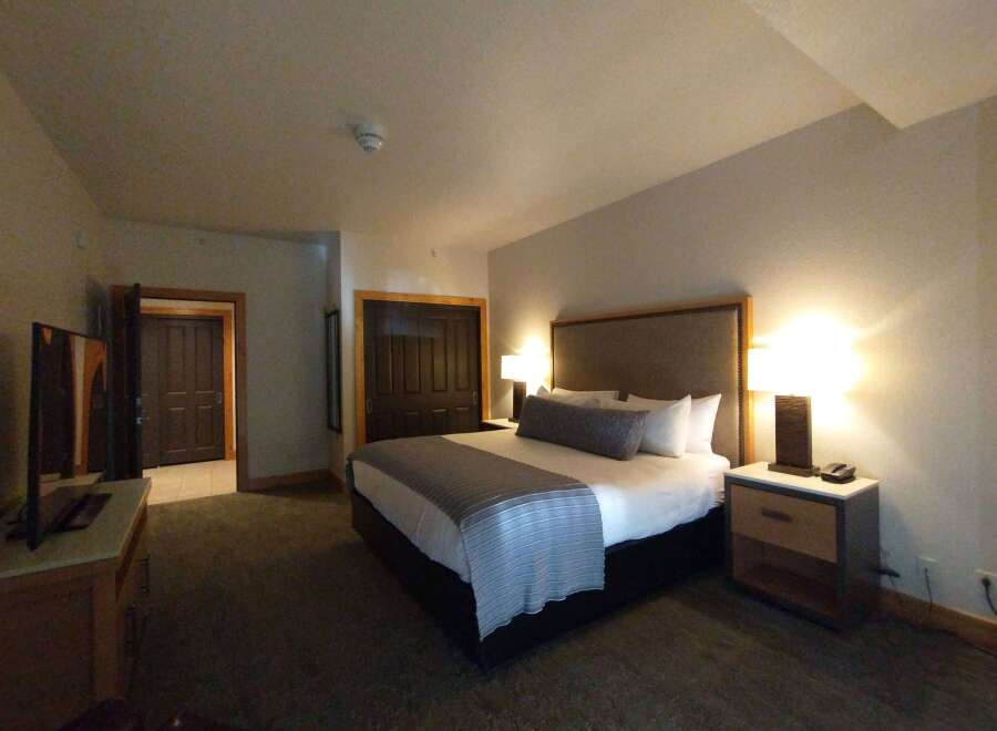 Experience comfort and style in this beautifully appointed hotel room, featuring a plush king-sized bed with crisp white linens and a decorative gray throw.