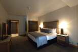 Experience comfort and style in this beautifully appointed hotel room, featuring a plush king-sized bed with crisp white linens and a decorative gray throw.