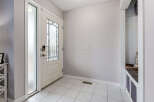 Step into a welcoming entryway featuring a stylish white door with frosted glass and decorative panels, complemented by sleek tile flooring.