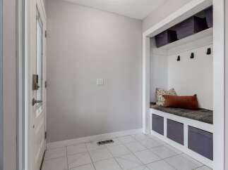 This entryway features a white door with a glass panel and a modern lock, leading into a space with light gray walls and tiled flooring.