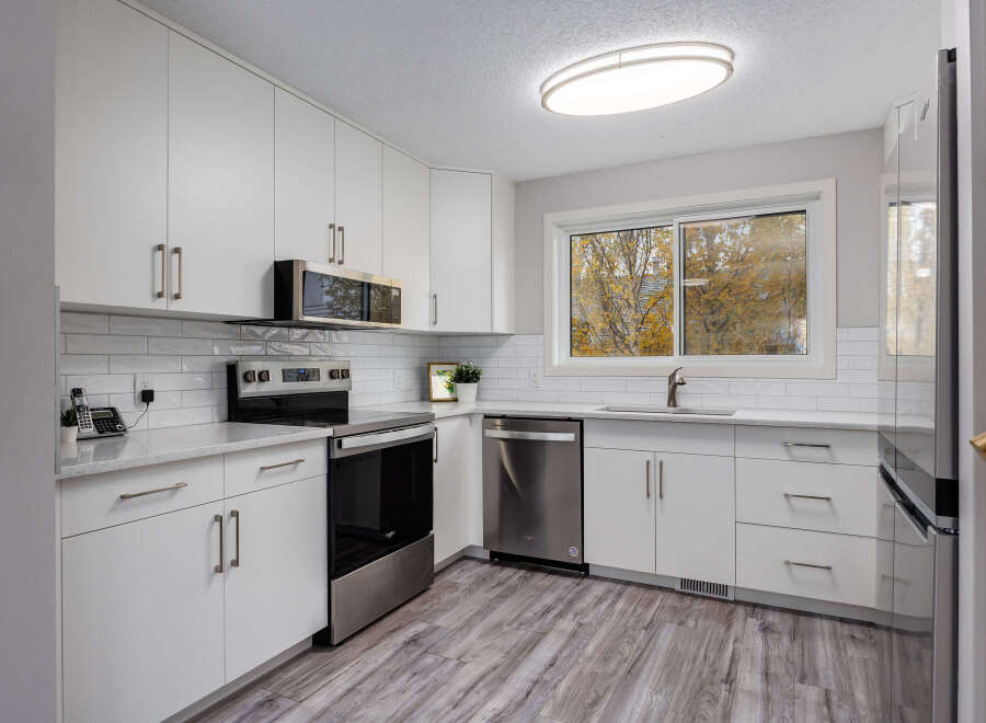 This modern kitchen boasts sleek white cabinetry and a stylish subway tile backsplash, creating a bright and airy atmosphere.