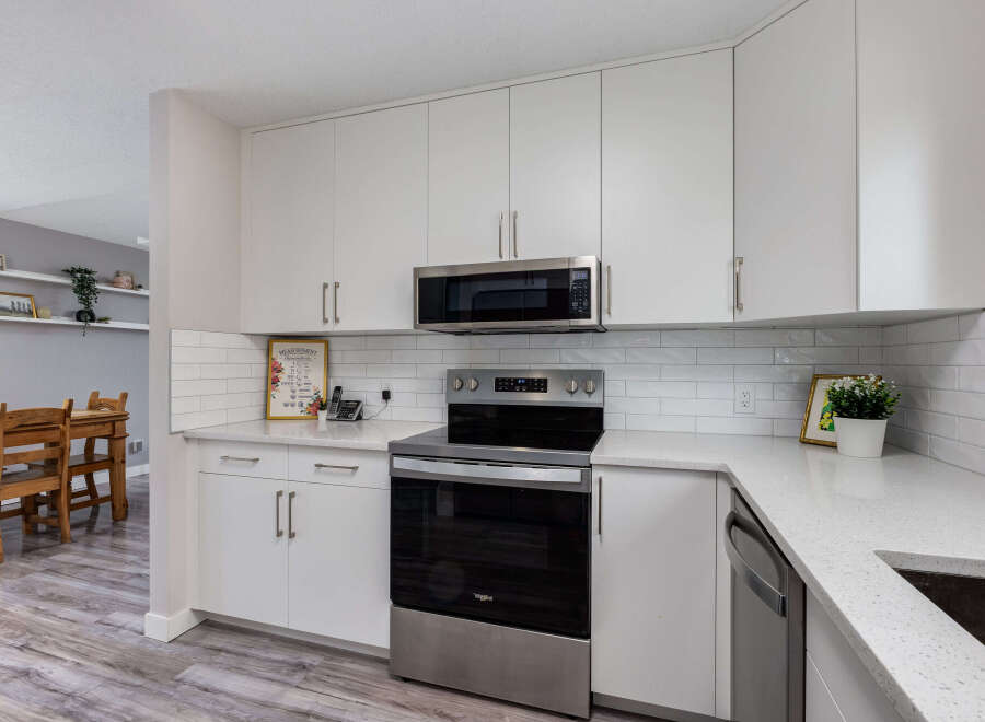 This modern kitchen boasts sleek white cabinetry and a stainless steel range, complemented by a subway tile backsplash.