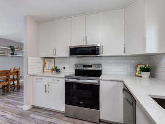 This modern kitchen boasts sleek white cabinetry and a stainless steel range, complemented by a subway tile backsplash.