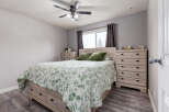 This bedroom features a light wood bed frame with built-in drawers, complemented by matching nightstands and dressers.