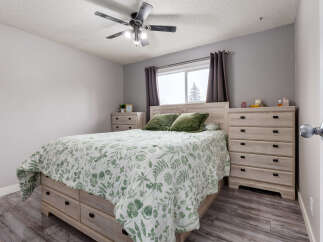 This bedroom features a light wood bed frame with built-in drawers, complemented by matching nightstands and dressers.