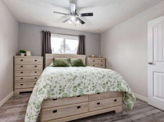 This charming bedroom features a spacious queen-size bed with a beautiful green floral comforter and plush green pillows.