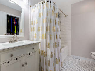 This charming bathroom features a white vanity with a brushed nickel faucet and a large mirror reflecting a closet with organized clothing.