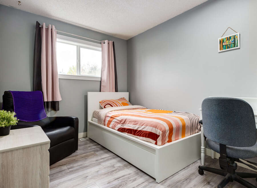 This cozy bedroom features a comfortable single bed with vibrant, striped bedding, perfect for a child or guest room.