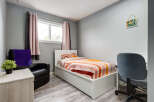 This cozy bedroom features a comfortable single bed with vibrant, striped bedding, perfect for a child or guest room.