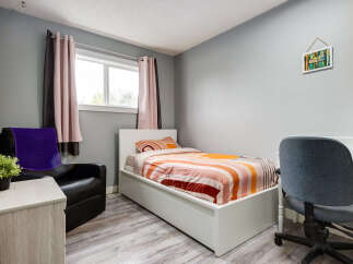 This cozy bedroom features a comfortable single bed with vibrant, striped bedding, perfect for a child or guest room.