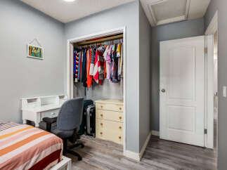 This bedroom features a convenient white desk with drawers and shelving, perfect for studying or working from home.