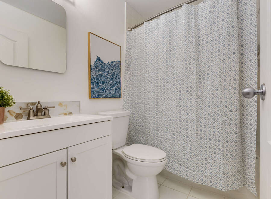 This bathroom features a clean white vanity with a modern faucet and a decorative hexagonal backsplash.