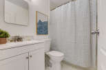 This bathroom features a clean white vanity with a modern faucet and a decorative hexagonal backsplash.