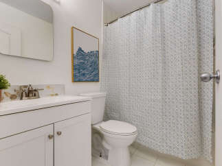This bathroom features a clean white vanity with a modern faucet and a decorative hexagonal backsplash.