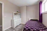 This cozy bedroom features a comfortable single bed adorned with a vibrant purple geometric-patterned comforter and a dark pillow.