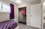 This bedroom features a cozy bed with a vibrant purple geometric-patterned comforter, complemented by matching purple curtains.