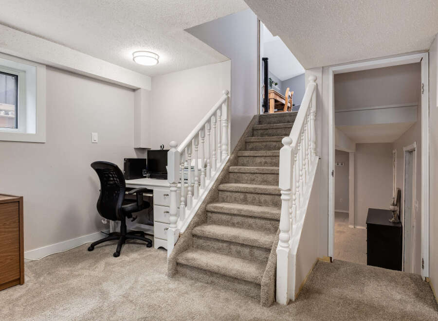 Discover a functional basement space featuring a dedicated home office area with a desk and chair, perfect for remote work or study.
