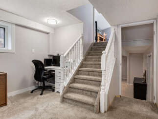 Discover a functional basement space featuring a dedicated home office area with a desk and chair, perfect for remote work or study.