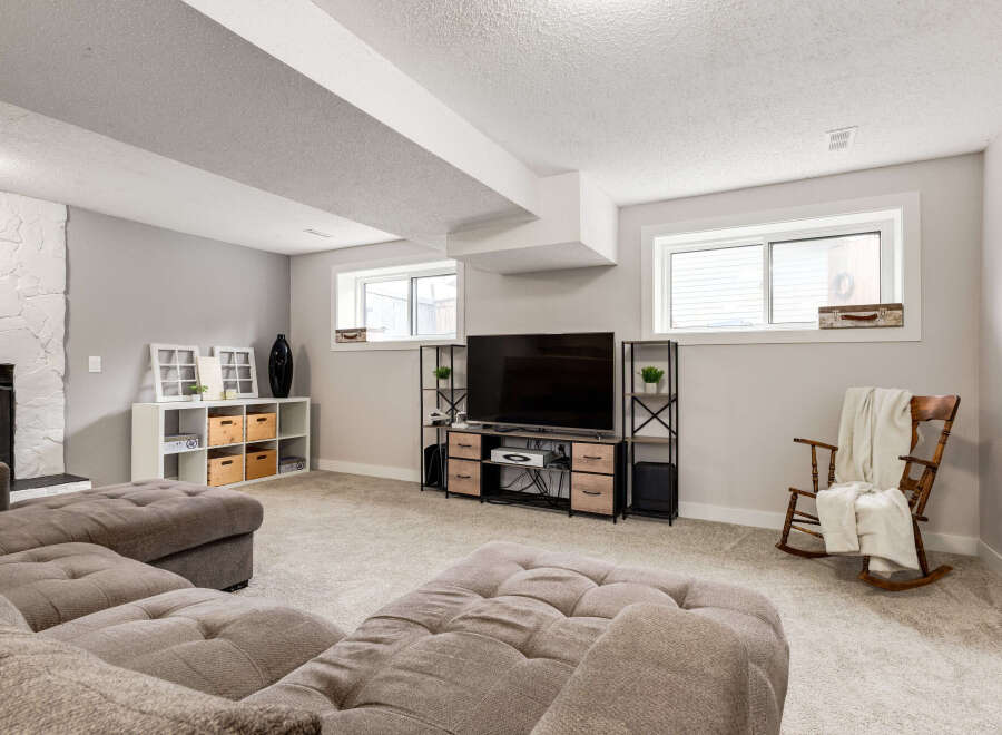 This finished basement offers a cozy entertainment space with a large sectional sofa and a modern media console featuring a flat-screen TV.