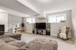 This finished basement offers a cozy entertainment space with a large sectional sofa and a modern media console featuring a flat-screen TV.