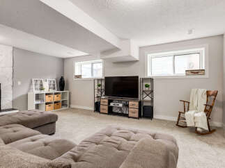 This finished basement offers a cozy entertainment space with a large sectional sofa and a modern media console featuring a flat-screen TV.