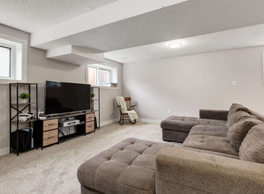 This basement living room features a large, comfortable sectional sofa perfect for family movie nights.
