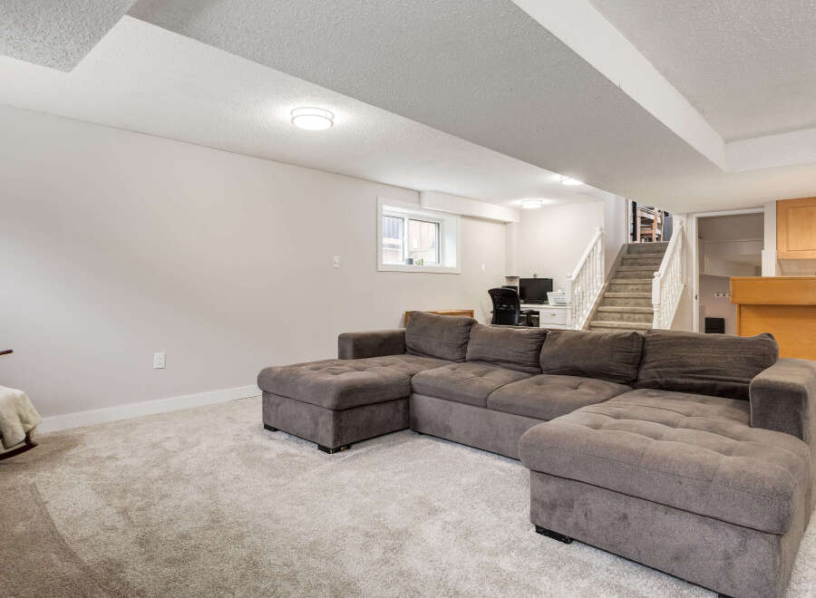 This spacious basement living area features a large, comfortable sectional sofa perfect for family gatherings or relaxing evenings.