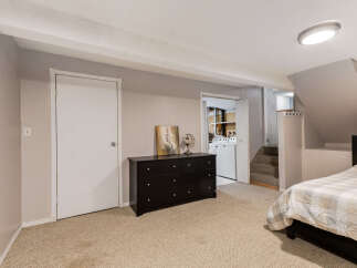 Discover comfortable living in this basement bedroom, featuring a plush carpeted floor and a convenient dresser for storage.