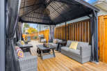 This spacious backyard features a covered gazebo with comfortable outdoor seating, perfect for entertaining guests or enjoying a quiet evening.