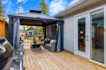 Step onto a spacious wooden deck, perfect for outdoor entertaining, featuring a covered gazebo with comfortable seating and a stylish coffee table.