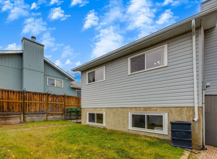 Discover this charming home featuring a well-maintained backyard with a wooden fence and lush green grass.