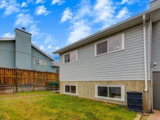 Discover this charming home featuring a well-maintained backyard with a wooden fence and lush green grass.