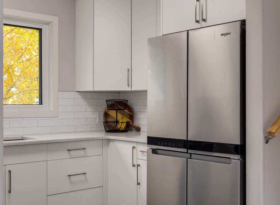 This modern kitchen features sleek white subway tile backsplash and light gray cabinetry, creating a bright and airy atmosphere.