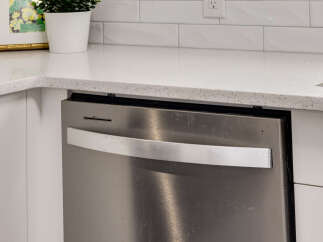 Discover a modern kitchen featuring a sleek stainless steel dishwasher integrated seamlessly with white cabinetry.