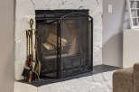 Cozy up by this inviting fireplace, featuring a rustic stone surround and a protective black mesh screen.