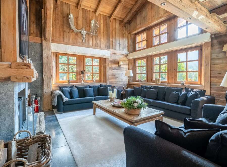 Experience rustic luxury in this stunning mountain lodge living room, featuring a grand stone fireplace and exposed wooden beams.