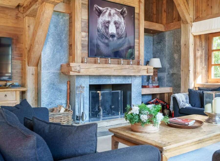 Experience rustic luxury in this stunning living room, featuring a grand stone fireplace adorned with a captivating bear portrait.
