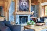 Experience rustic luxury in this stunning living room, featuring a grand stone fireplace adorned with a captivating bear portrait.