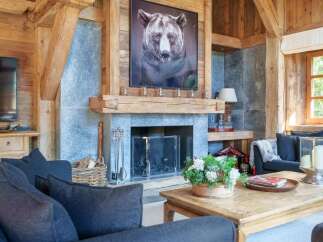 Experience rustic luxury in this stunning living room, featuring a grand stone fireplace adorned with a captivating bear portrait.