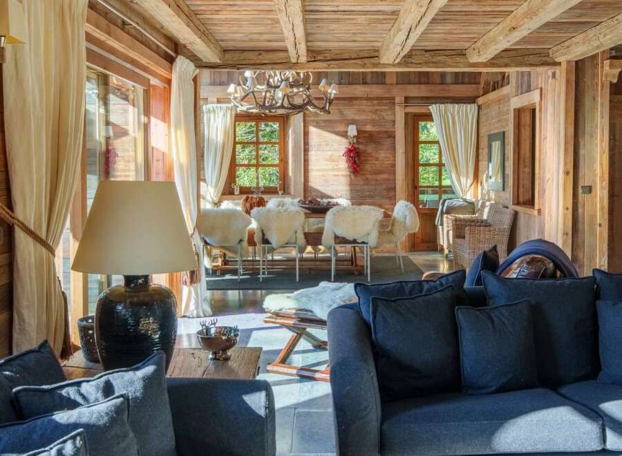 Experience rustic luxury in this charming wooden chalet, featuring a spacious living area with plush seating and a cozy dining space perfect for gatherings.