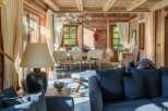 Experience rustic luxury in this charming wooden chalet, featuring a spacious living area with plush seating and a cozy dining space perfect for gatherings.